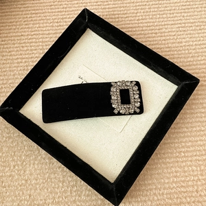 Close-up of elegant black velvet hair clip with a sparkling rhinestone rectangular buckle
