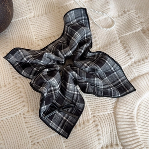 Classic black and white plaid bow scrunchie with refined edge on a textured background