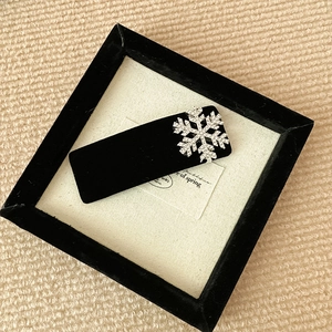 Detail of velvet hair clip with rhinestone snowflake decoration on cozy textile background