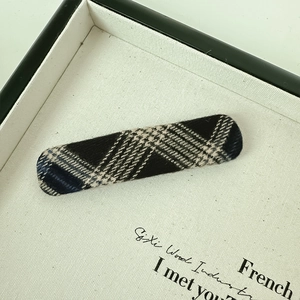 Detailed view of rectangle plaid hair clip with blue and beige woolen fabric texture