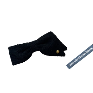 Elegant black tweed asymmetrical bow hair clip with gold button on a white background