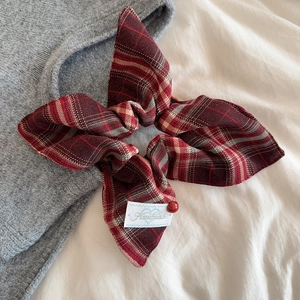 Red plaid checkered bow hair scrunchie with handmade label on soft fabric background