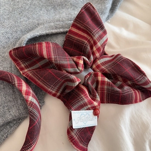 Detail of red plaid bow scrunchie and headband set on cozy knit background