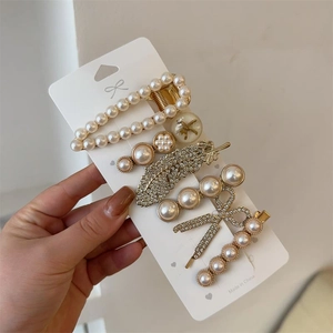 Lot de 7 barrettes dorées avec perles et strass présentées sur une carte support
