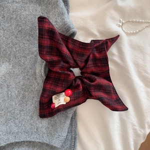Detail of red and black plaid fabric scrunchie with brand label and decorative beads