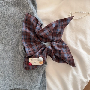 Detail of checkered plaid bow hair scrunchie with colorful beads and white fabric label