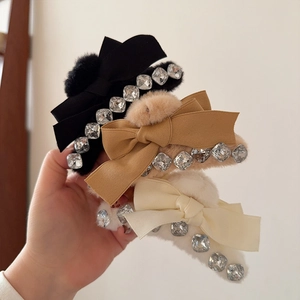 Détail de pinces à cheveux en peluche avec nœuds et strass en noir, beige et marron