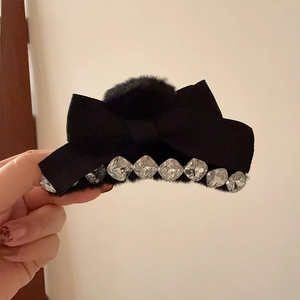 Détail d'une pince à cheveux en velours noir avec pompons et strass brillants décoratifs