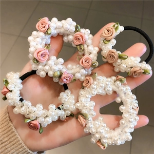 Gros plan d'élastiques à cheveux en perles avec roses roses en tissu et feuilles vertes