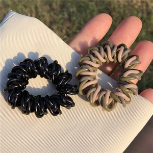 Vue détaillée d'élastiques à cheveux en spirale noirs et vert armée sur support blanc