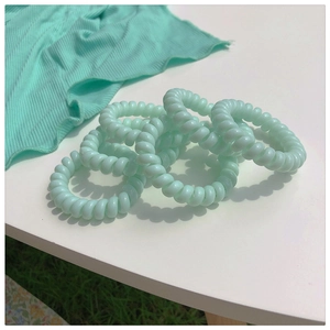 Détail des chouchous spirales vert menthe sur un fond en tissu de couleur assortie