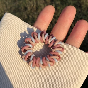 Détail de l'élastique spirale rose clair et bleu-gris sur papier beige texturé