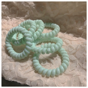 Vue détaillée d'élastiques spirales vert menthe sur un tissu en dentelle beige