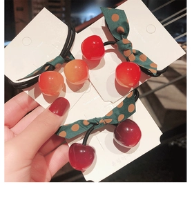 Detailed close-up of elastic hair ties with 3D cherry charms and polka dot bows
