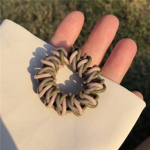 Détail d'un élastique spirale vert olive et rose-brun sous la lumière du soleil