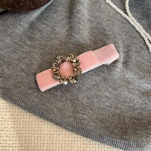 Close-up of pink velvet bow hair clip with gray crystal rhinestones on fabric
