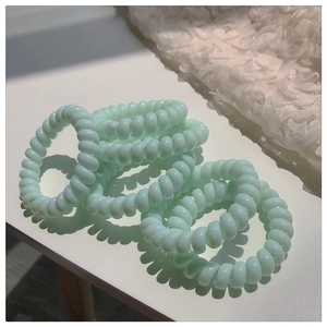 Gros plan d'élastiques à cheveux spirale vert menthe sur un tissu en dentelle blanche