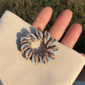Vue détaillée d'un élastique à cheveux en fil de téléphone tressé bleu et gris à la main