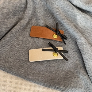 Détail de barrettes en velours avec nœuds noirs et pendentifs dorés gravés en gros plan
