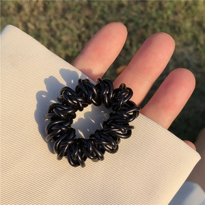 Gros plan d'un chouchou spirale noir tenu à la main sur un fond en tissu doux
