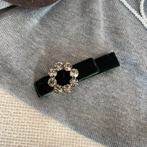 Dark green velvet hair clip with grey rhinestones on grey and beige background