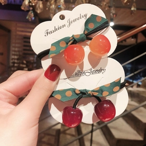 Handheld cherry resin hair tie set with polka dot bows on a white cloud display card