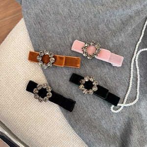 Close-up of velvet bow hair clips with rhinestone circles in pink, green, brown, and black