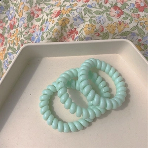 Lot de 3 élastiques spirales vert menthe sur plateau fleuri de style minimaliste
