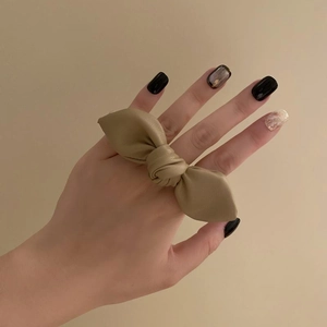 Detailed close-up of a premium leather bow tie hair accessory in a soft khaki finish