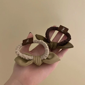Elegant faux leather bow hair ties in beige and olive green with SMLE label
