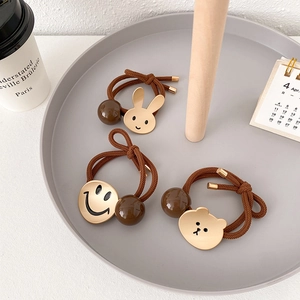 Detail van elastische haarelastiekjes met beer, smiley en gouden konijn hangers op dienblad