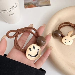 Detailopname van haarelastiekjes met een gele smiley en een beige konijntje