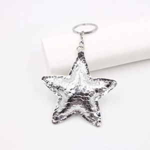 Close-up of silver star keychain charm with cracked leather texture and stitching