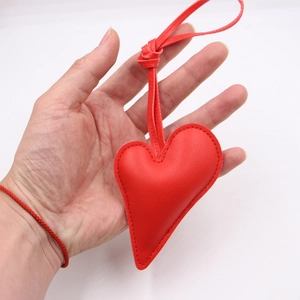 Red leather heart-shaped pendant keychain held in hand with refined stitching detail