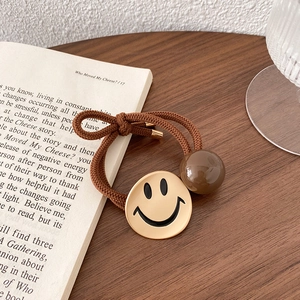 Detailopname van bruine haarelastiek met geel smiley-kraaltje op een open boek