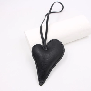 Detailed view of black heart-shaped leather charm with litchi texture and stitching