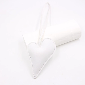Close-up of white heart-shaped leather bag charm with stitched edges and long lanyard strap