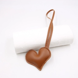 Detail of heart-shaped dark brown leather pendant with top stitching and long leather cord