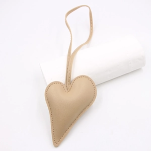 Detail of beige leather heart charm with meticulous stitching and long matching lanyard