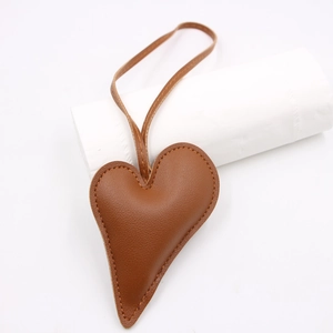 Brown heart-shaped leather charm with refined stitching and adjustable matching lanyard
