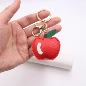 Handheld red apple PU leather keychain with gold ring and green leaf on white background