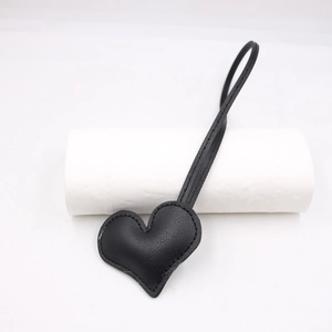 Macro shot of black pebbled leather heart pendant with fine stitching and long neck strap