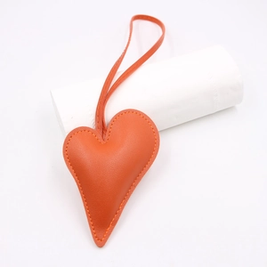 Close-up of heart-shaped orange leather pendant with detailed hand-stitched edges