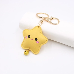 Close-up of yellow leather star keychain with smiling face and golden bell detail