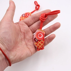 Close-up of a red carp leather charm with detailed scales and a red hanging cord