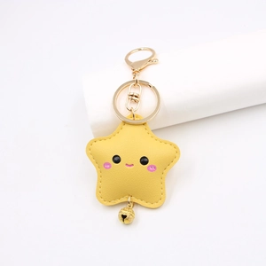 Detailed view of yellow leather star keychain with cute smiley face and golden bell charm