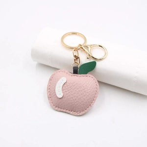 Close-up of pink PU leather apple keychain with lychee texture and gold lobster clasp