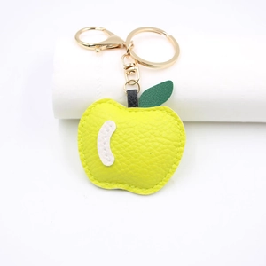 Detailed view of yellow lychee grain leather apple keychain with golden metal clasp hardware