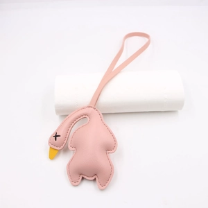 Detail of pink leather swan charm featuring black X embroidery and fine stitching
