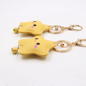 Detail of yellow star keychain with cute smiley face, golden bell, and lobster clasp